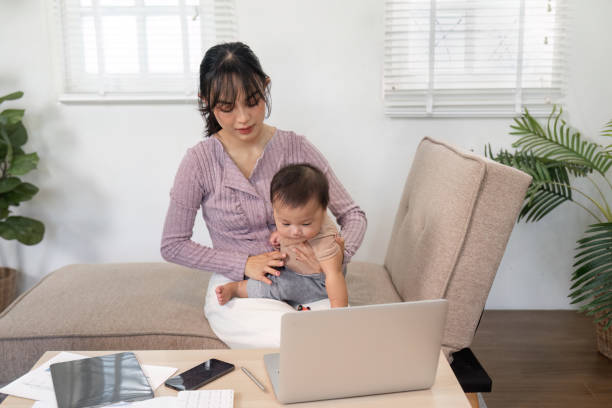 istock Engaged mother interacting with her baby while working on a laptop at home 2196488537