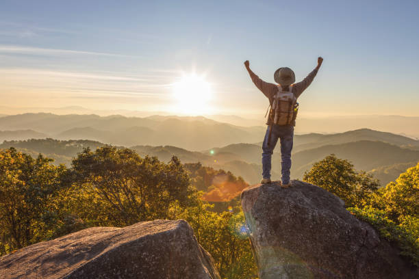 istock Hiker with backpack raised hands standing on top mountain sunset background. Hiker man hiking living healthy active lifestyle. 2196496011