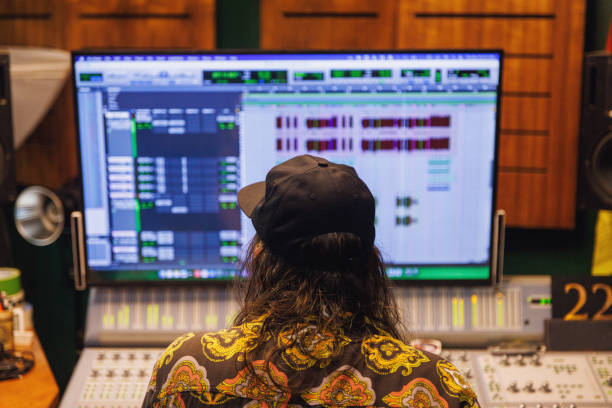 Producer, audio engineer uses a control panel and screen to record a track of a new album in a recording studio, in a soundproof room. Image producer, designer in working process