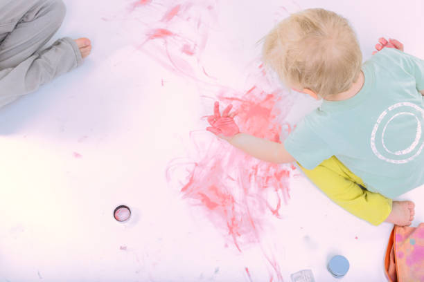 istock Toddler painting with red finger paint on white background 2196498633