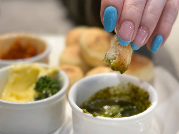 Stock photo showing close-up view of some fresh dough balls that are being served as a starter at a restaurant with a small dishes of garlic butter, garnished with parsley, red and green pesto.