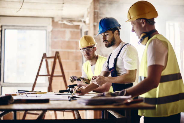 istock Team of manual workers examining housing project while working at construction site. 2196507228