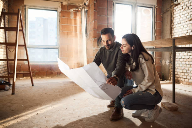 istock Smiling couple analyzing plans at their renovating apartment. 2196507246