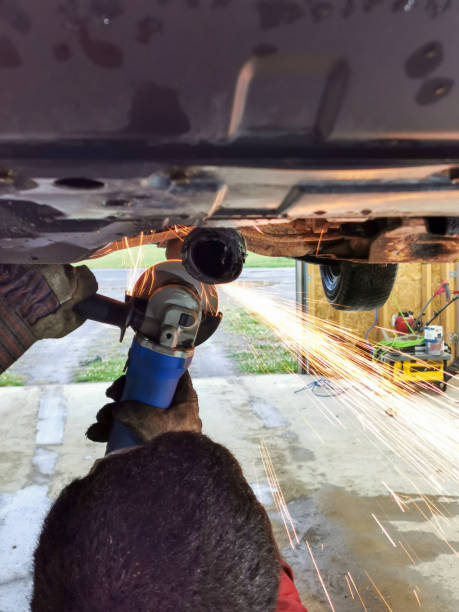 istock Auto Mechanic Grinding Underneath a Car with Sparks Flying in a Garage Workshop 2196507364