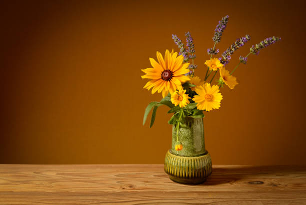 Still life, yellow flowers in a ceramic vase and lavender on a wooden table