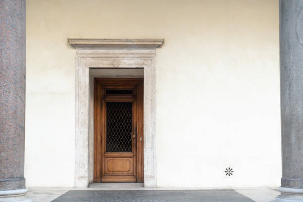 Old wooden door on a white plaster wall of medieval stone building between two gray columns