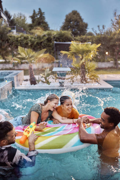 istock Young cheerful friends having fun on inflatable raft at the pool. 2196507713