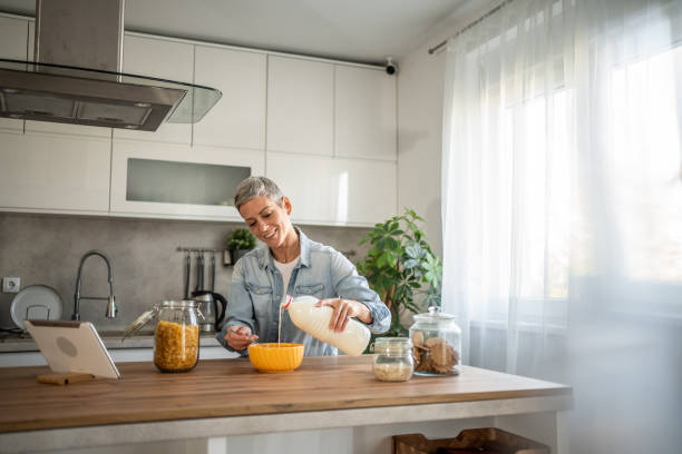 istock Happy woman with short hair eating breakfast cereal and using digital tablet 2196508629