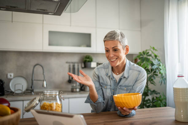 istock Happy woman with short hair eating breakfast cereal and using digital tablet 2196508719