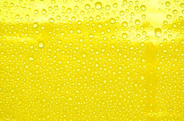 Detailed View of Droplets Resting on Yellow Background.
