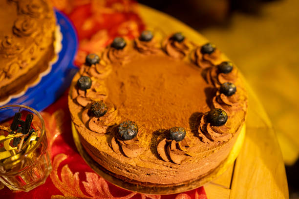 A beautifully decorated homemade chocolate cake topped with blueberries and chocolate frosting, displayed on a festive table with a red tablecloth. This rich dessert exudes elegance and is perfect for special celebrations and gatherings.