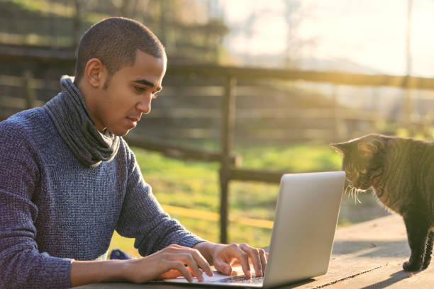 istock Young adult man working on laptop with curious cat 2196513272