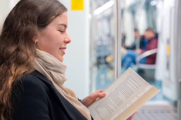 istock Side view Young Woman Reading a Book While Traveling on a Subway Train., 2196516597