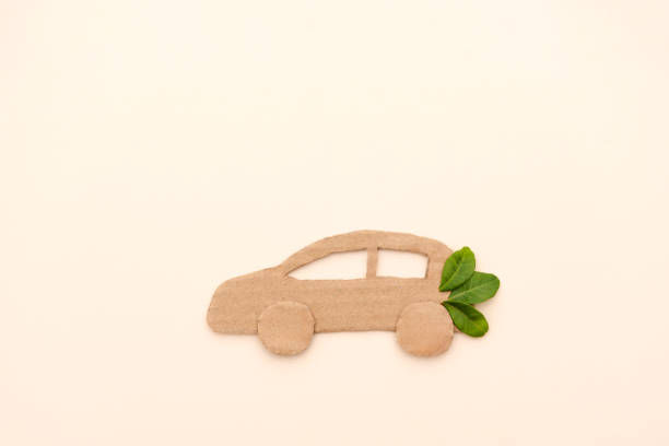 istock Cardboard car with green leaves representing eco-friendly transportation on a neutral background 2196517212