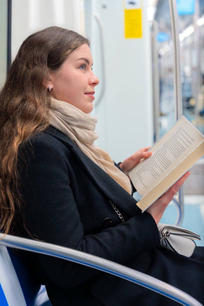 istock Side view Young Woman Reading a Book While Traveling on a Subway Train.,Vertical 2196517320
