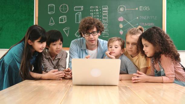 istock Caucasian teacher and diverse student looking at laptop at classroom. Pedagogy. 2196519023