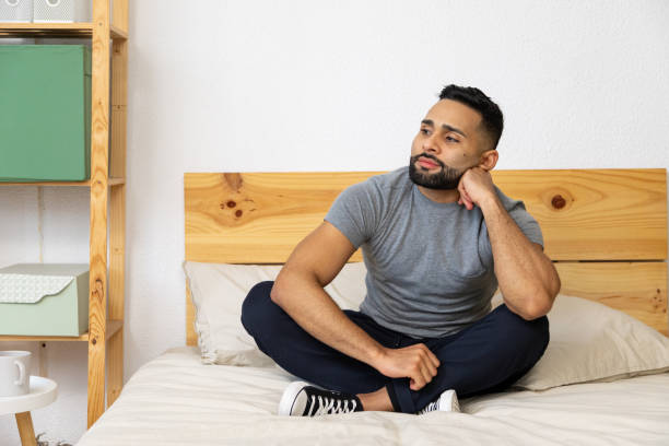 istock Young man relaxing on bed in thoughtful pose 2196521282