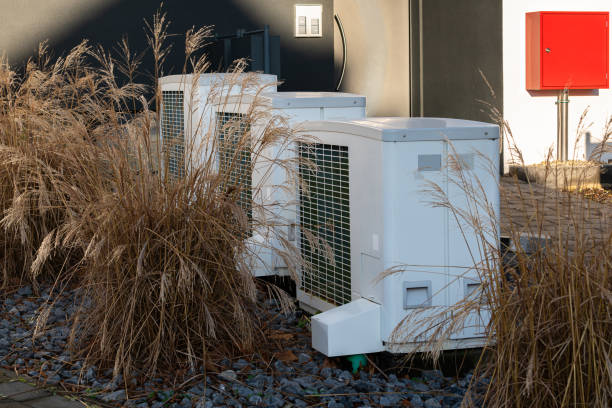 istock Three air conditioning units surrounded by tall grass near a building 2196523422