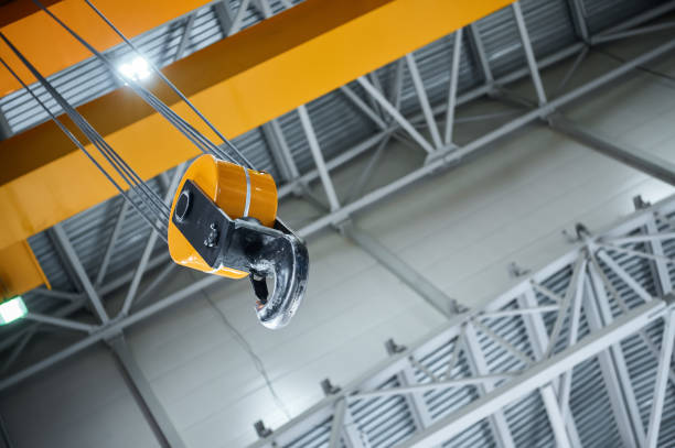 istock Hook assembly of yellow crane hangs under ceiling in shop 2196523919