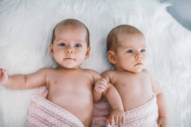 istock Adorable Twin Babies Lying on Soft White Fur 2196523971