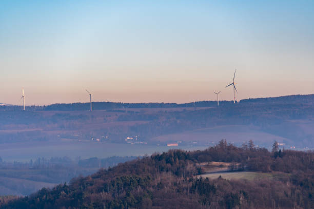 istock Wind turbines stand tall on rolling hills during a stunning sunset. The sky transitions from deep blue to vibrant shades of purple and red, creating a dramatic and peaceful scene 2196524430