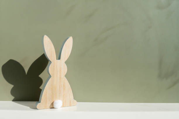 istock Minimalistic creative Easter concept. Two Easter bunnies under symbolic roof on green background. Celebration Easter holiday at home with family. Poster or greeting card 2196529065