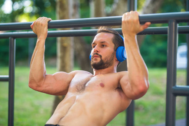 istock Young man wearing headphones doing pull-ups in a park 2196529484