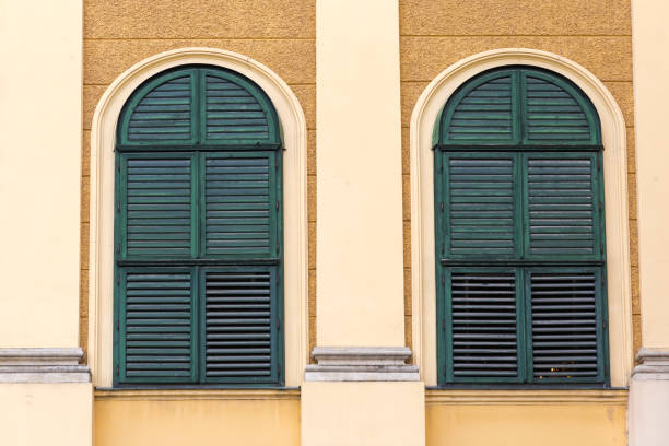 istock Arched windows with closed green wooden shutters in yellow wall 2196531007