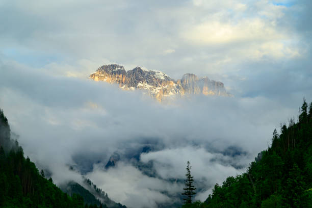 Monte Civetta mountain in the Dolomites surrounded by clouds during sunset after a beautiful springtime day. The Civetta is a prominent and major mountain of the Dolomites, and is popular amongst mountaneers to climb as its one of the highest rock formations in Europe.