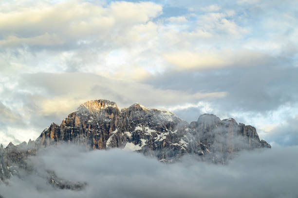 Monte Civetta mountain in the Dolomites surrounded by clouds during sunset after a beautiful springtime day. The Civetta is a prominent and major mountain of the Dolomites, and is popular amongst mountaneers to climb as its one of the highest rock formations in Europe.