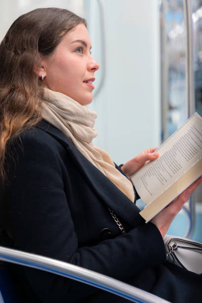 istock Side view Young Woman Reading a Book While Traveling on a Subway Train.Vertical 2196534416