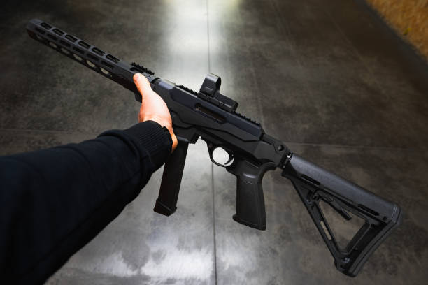 istock Tactical rifle for 9mm pistol caliber with red dot sight in mans hand at shooting range. 2196537459