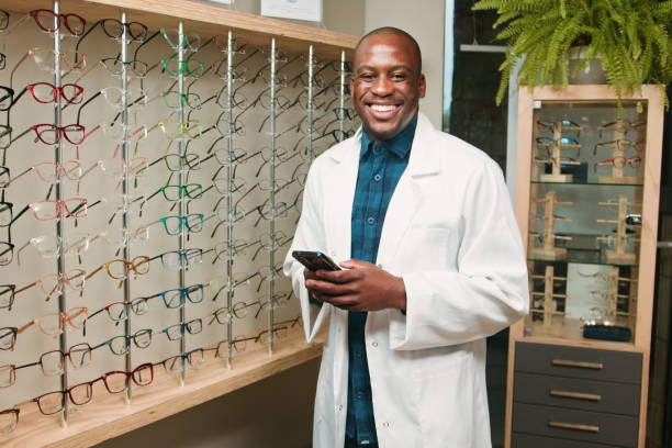 istock Smiling Optometrist Standing in Eyewear Store Holding Phone 2196537941