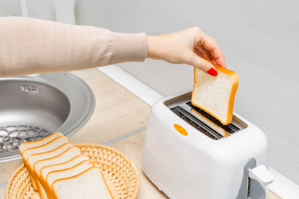 istock woman's hand putting bread into the toaster. 2196538923