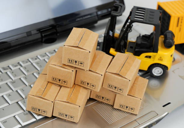 istock Shipping carton boxes and forklift truck on laptop computer keyboard. 2196540354