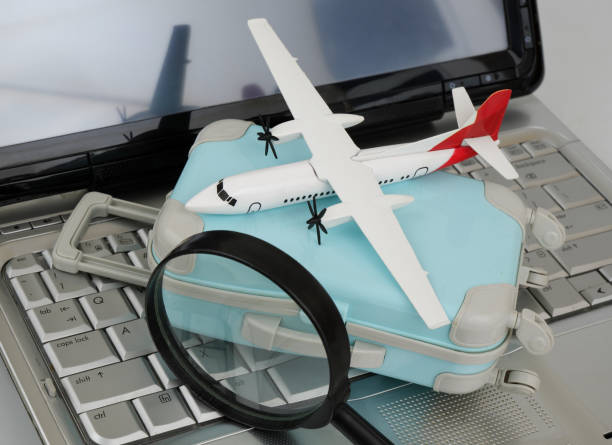 istock Airplane under magnifying glass on travel suitcase on laptop keyboard. 2196540399
