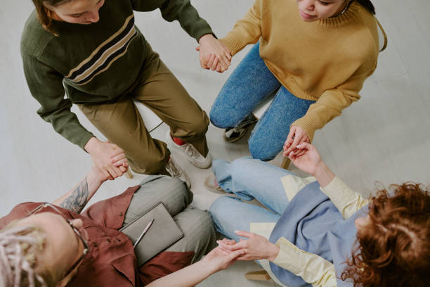 istock Group Holding Hands in Circle on Floor Indoors 2196542651