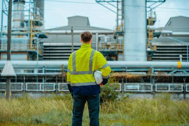 istock Worker observing industrial plant operations while standing in a grassy area during daylight hours 2196544179