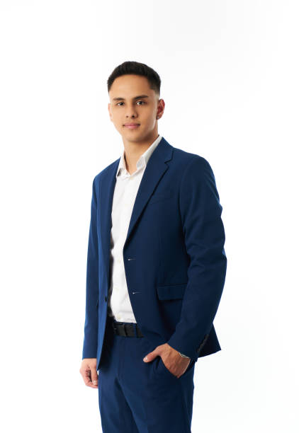Studio portrait of a confident young businessman wearing a blue suit and white shirt, standing with his hand in his pocket