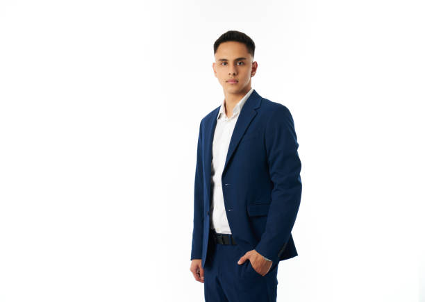 Studio portrait of a confident young businessman wearing a blue suit and white shirt, standing against a white background