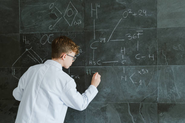 istock Focused schoolboy writing on chalkboard in classroom 2196546853