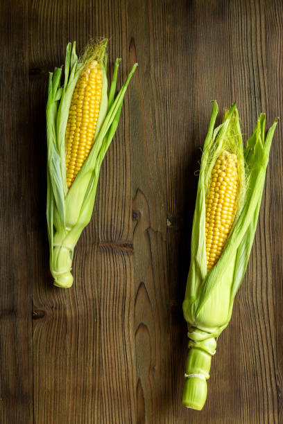 istock Two fresh yellow corns on the cob, top view. Vegetable background 2196547829