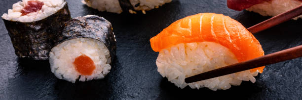 istock Sushi assortment panorama on a black background. Salmon nigiri with chopsticks 2196551479
