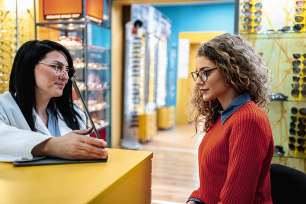 istock Optician helping young woman choosing eyeglasses in optical store 2196551987