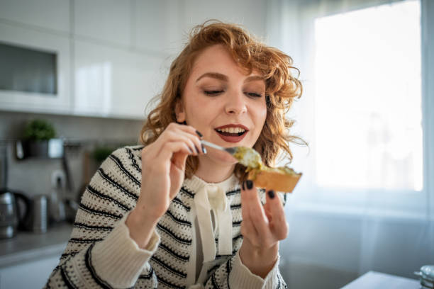 istock Young woman making and eating bruschetta in her kitchen 2196560223