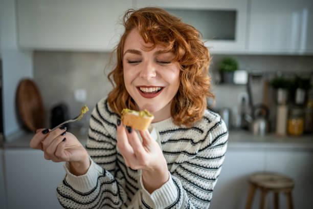 Young woman eating fresh avocado bruschetta in her kitchen