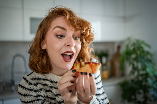 istock Young woman making and eating bruschetta in her kitchen 2196560348