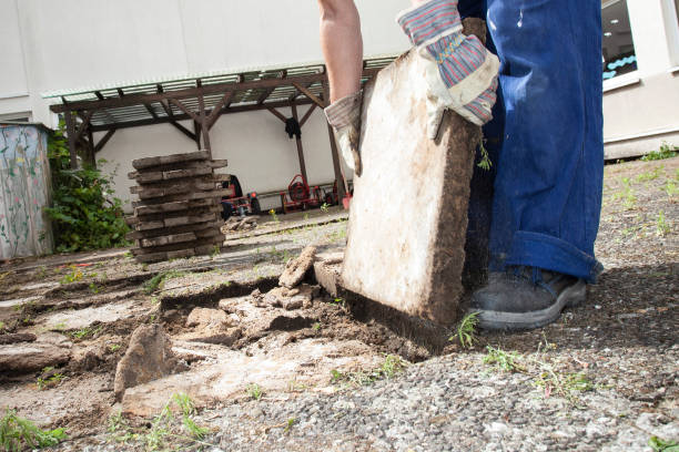 Break up and removing old paving stones from the ground in a backyard