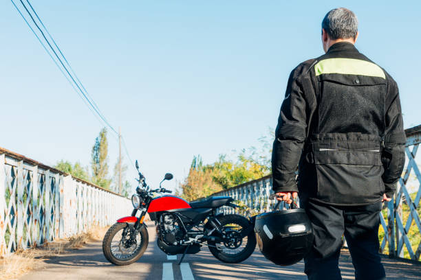 istock man on his back looking at a motorcycle with a helmet in his hand 2196564401