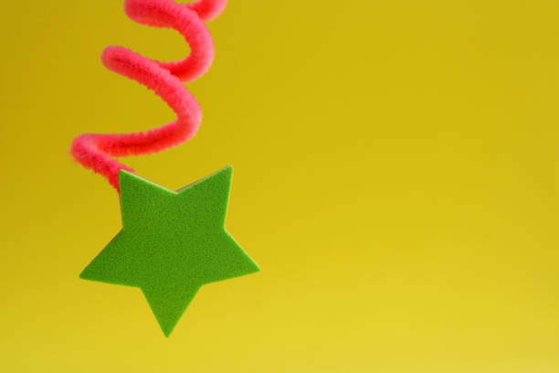 Christmas decoration - Closeup of one red star hanging on a Xmas tree branch with cream background for copy space.